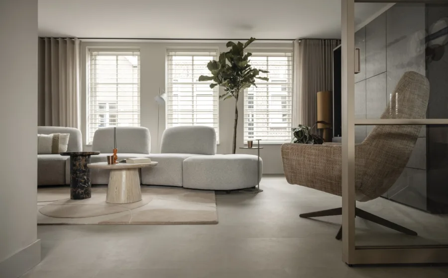 woonkamer met dubbele raamdecoratie: overgordijnen en witte jaloezieën.