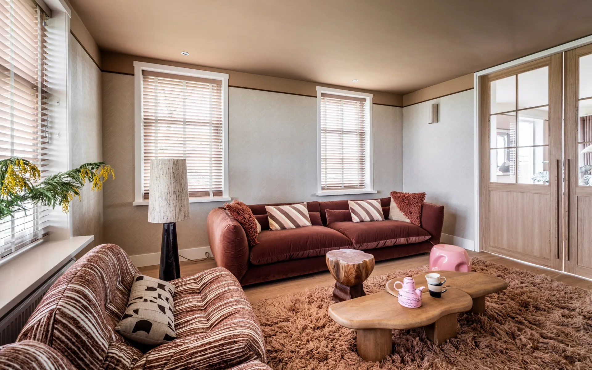 Warmkleurijke woonkamer met fluffy vloerkleed en houten jaloezieën