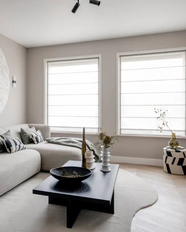 Elegante, witte vouwgordijnen die het zonlicht zacht filteren in een moderne woonkamer.