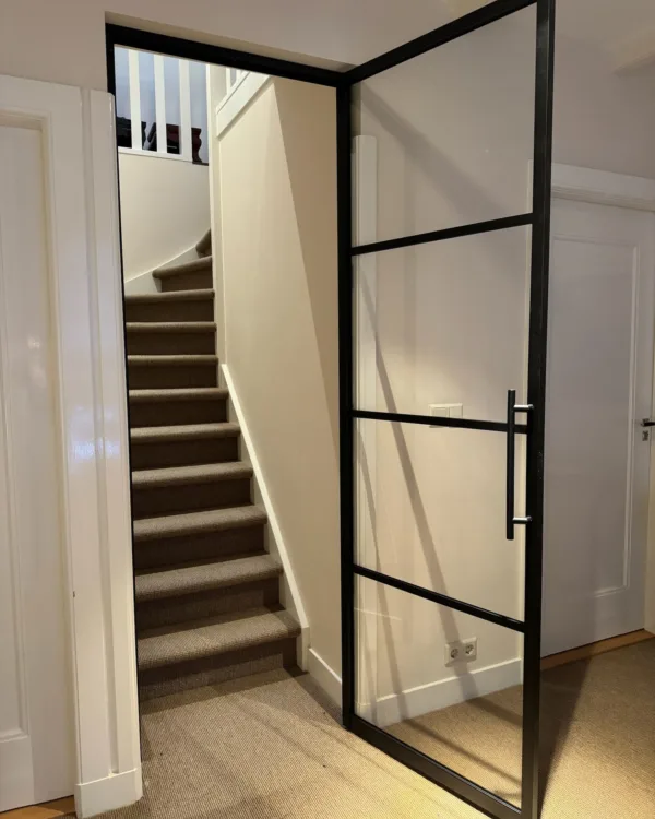 Prachtige SolidDoor metalen deur met zwart frame en grote glasvakken voor extra daglicht in de hal en trap.