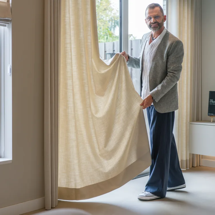 Frans Uyterlinde in de woonkamer met beige Inside gordijnen