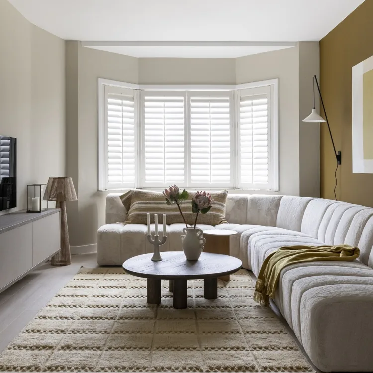 Woonkamer met erker en witte shutters op maat.